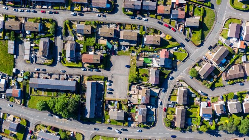 Luftaufnahme einer Drohne von kleinen gewundenen Straßen und Wegen in einem Wohngebiet einer Kleinstadt