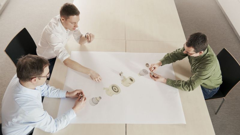 Drei Projektmitarbeiter sitzen an einem Tisch und besprechen die Forschungsergebnisse.