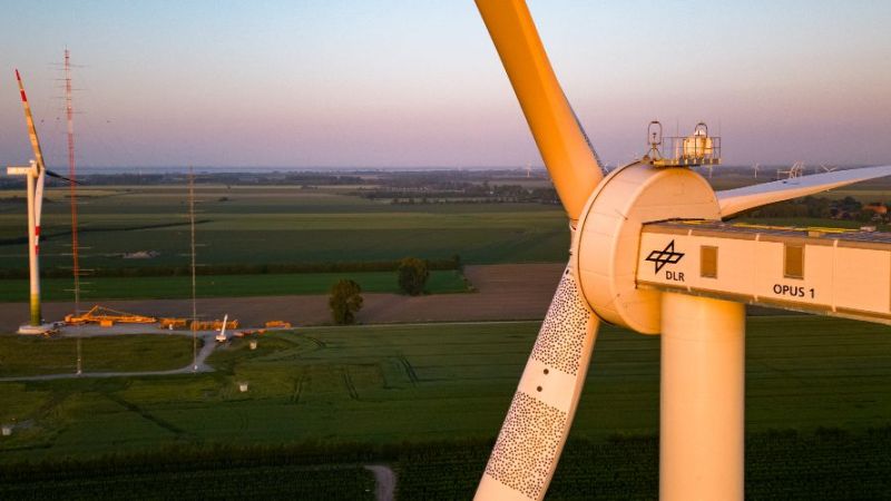 Eine Windenergieanlage im Vordergrund, im Hintergrund sieht man eine zweite Windenergieanlage und einen Windmessmast.