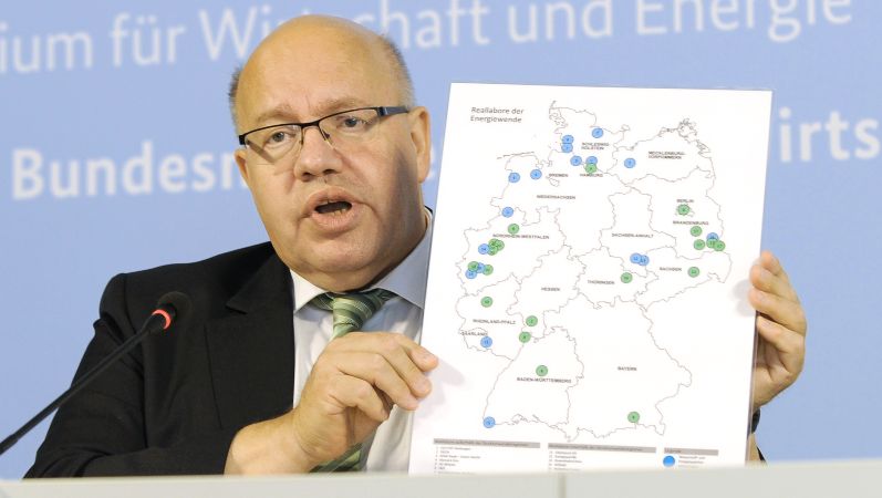 Minister Peter Altmaier hält eine Deutschland-Karte mit den Standorten der Gewinner des Ideenwettbewerbs hoch