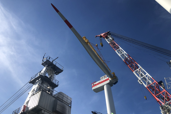 The installation of the rotor blades entails gigantic dimensions. The rotor blades, here about 75 metres long, have to be placed in the nacelle, which is over a hundred metres above the water surface. Measured data collected in the process helps to find the right time windows. One of the rotor blades has already been successfully installed here. The measured data collected in the process can be used for further installations.