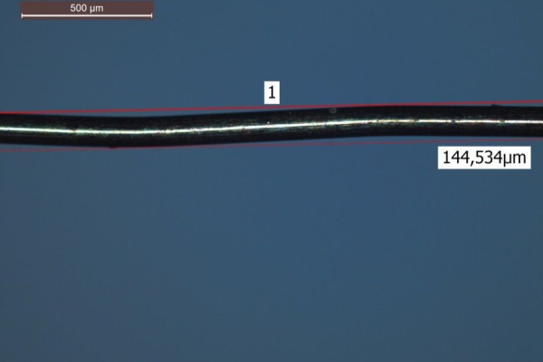 The photo shows a microscopic image of a structured wire.